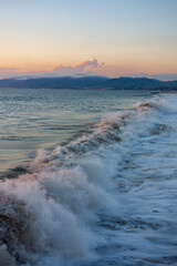 Waves crashing during sunset with the Santa Monica Mountains, and Malibu in the background