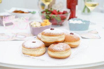 Warmth of Hanukkah. Beautifully Set White Wooden Table with Luscious Strawberries, and Traditional Sufganiyot - Fluffy Donuts with Powdered Sugar and Delectable Jam.