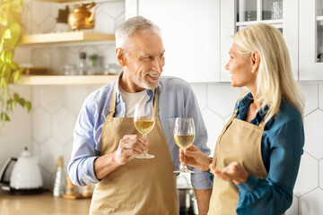 Romantic Senior Couple Drinking White Wine Together In Kitchen