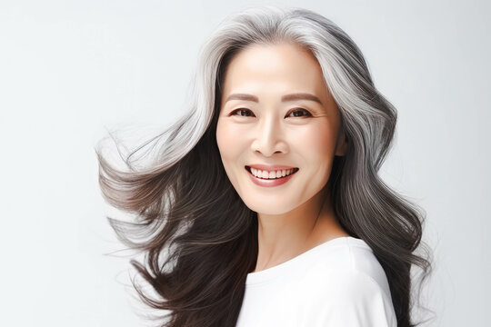 Japanese adult woman with smooth healthy face skin. Beautiful aging mature asian woman with long gray hair and happy smiling touch face. Beauty and cosmetics skincare advertising concept.