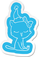 quirky cartoon  sticker of a cat with bow on head wearing santa hat
