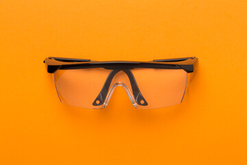 Safety glasses on color background, top view