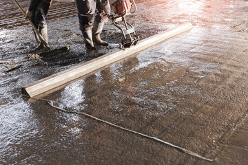 Workers uses vibrating machine to level cement mortar for floors. Concrete screed for buildings,...