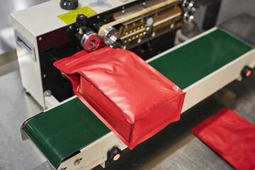 Close up of red plastic bag in packaging machine at food production factory, copy space