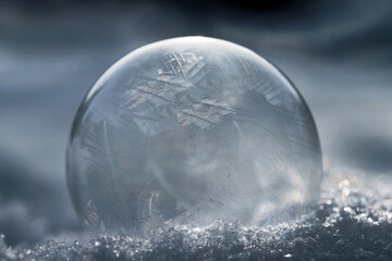 Eine gefrorene Seifenblase mit Muster im kalten Schnee