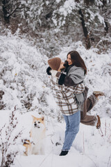 Happy young couple with akita dog in forest on winter and snowly day
