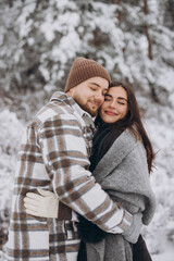 A young happy and loving couple walking in a winter snowy forest in the mountains