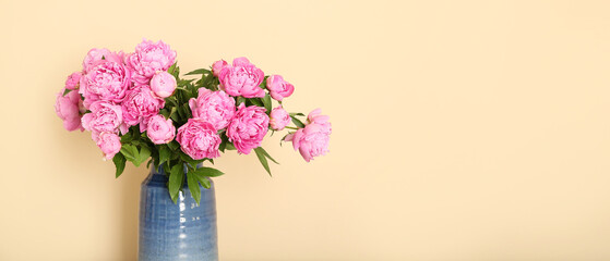 Vase with pink peonies on beige background with space for text