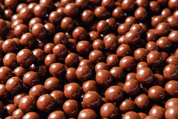 Closeup brown dragee, chocolate covered nuts, sweet candy background