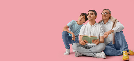 Happy little boy, his dad and grandfather reading book on pink background with space for text