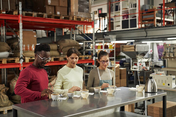 Diverse group of three young experts inspecting coffee quality during cupping process in artisanal...