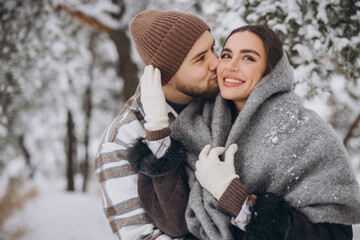 Portrait of a young happy and loving couple having fun in a snowy forest