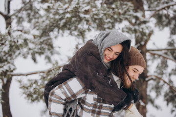 A young happy and loving couple is having fun in a snowy forest in winter.