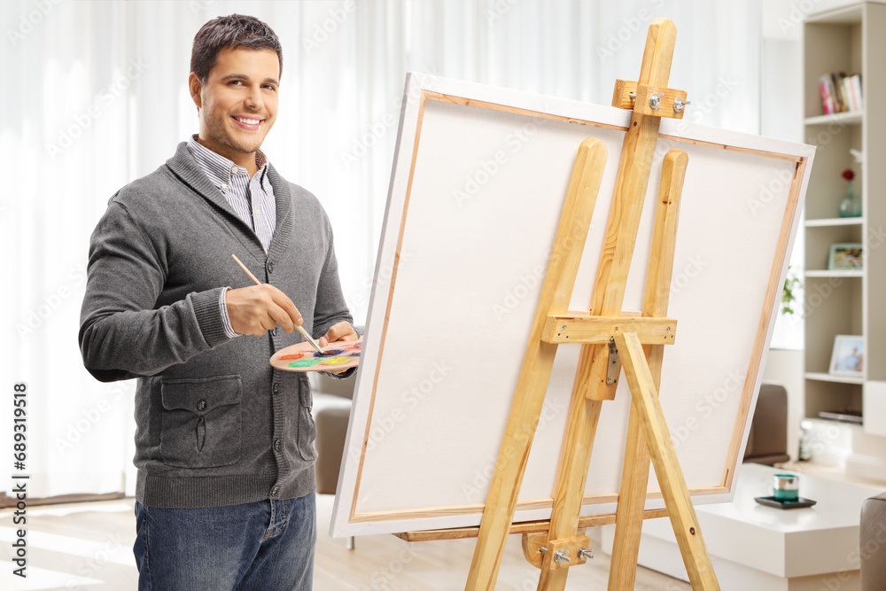 Wall mural Young man painting on a canvas at home