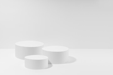 Abstract stage mockup with set of three round podiums in hard light for presentation cosmetic products, goods, advertising, design on white background. Abstract scene in light modern minimal style.