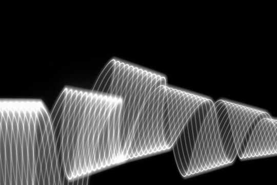 White neon glowing wave of light as curls or spirals with smooth stripes on black background. Abstract background with motion light effect, light painting in disco party style.