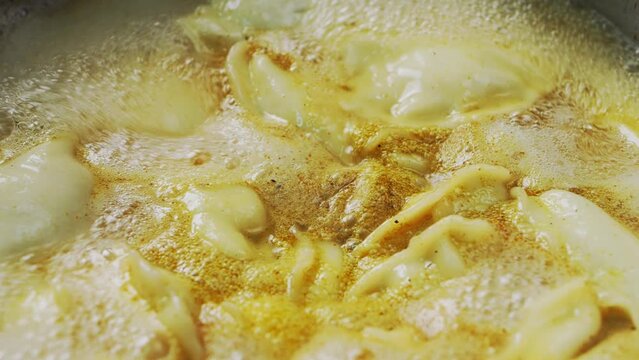 Vareniki dumplings are cooked in a saucepan in boiling water with cumin and turmeric. Close-up.