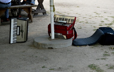 A close up on two accordions, a white and a red one located next to a metal pole and a concrete...