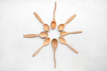 Frame made of different wooden spoons on light background