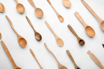 Different stylish wooden spoons on light background