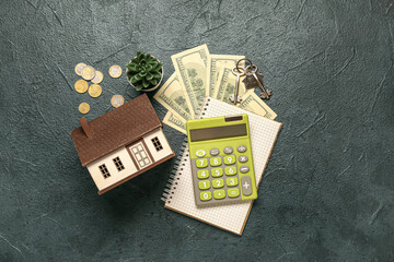 Calculator, house model, keys, money and houseplant on dark background. Mortgage concept