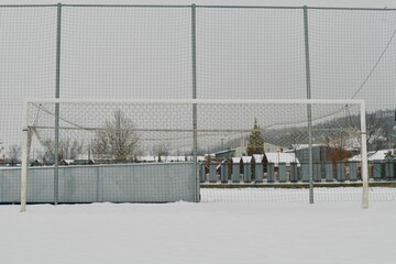 Fototapeta na wymiar A snow-covered football goal. The concept of the end of the football season, the football league and the end of the sports season