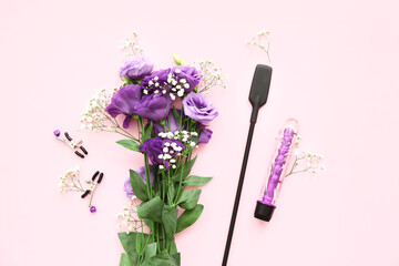 Sex toys and beautiful flowers on pink background
