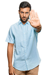 Handsome hispanic man wearing casual clothes doing stop sing with palm of the hand. warning expression with negative and serious gesture on the face.