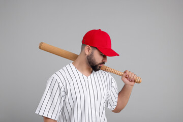 Man in stylish red baseball cap holding bat on light grey background