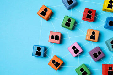 Teamwork. Wooden cubes with human icons linked together symbolizing cooperation on light blue...