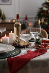 Christmas table setting with burning candles, appetizers and dishware indoors