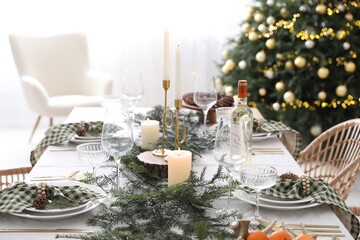 Christmas table setting with festive decor and dishware in room