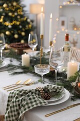 Christmas table setting with festive decor and dishware in room