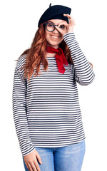 Young beautiful woman wearing french look with beret smiling happy doing ok sign with hand on eye looking through fingers