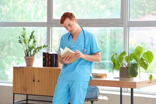 Male medical student reading book in library