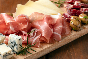 Tagliere con vari antipasti italiani: prosciutto crudo, gorgonzola, salame, pecorino e olive - cibo...