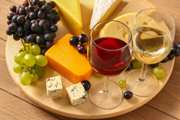 Board with tasty cheese, grapes and glasses of wine on wooden background