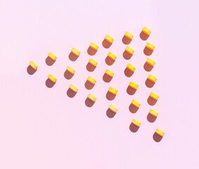 Many yellow pills on pink background
