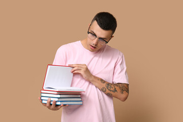 Handsome young man with books on beige background