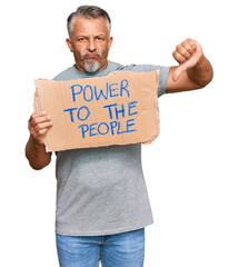 Middle age grey-haired man holding power to the people banner with angry face, negative sign showing dislike with thumbs down, rejection concept