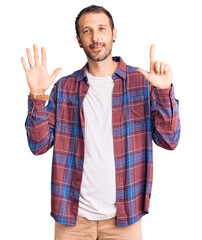 Naklejka premium Young handsome man wearing casual clothes showing and pointing up with fingers number seven while smiling confident and happy.