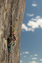 Person climbing in high mountains with yellow jacket rope and helmet in nature, confidence and risk, safety