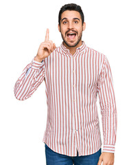 Young hispanic man wearing business shirt pointing finger up with successful idea. exited and happy. number one.