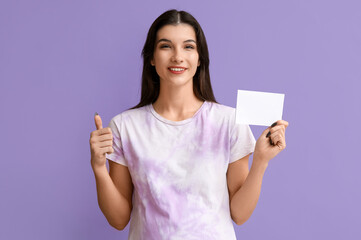 Pregnant woman with voting paper showing thumb-up on lilac background