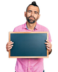 Hispanic man with ponytail holding blackboard looking at the camera blowing a kiss being lovely and sexy. love expression.