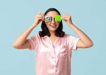 Beautiful young woman with condoms on blue background. Safe sex concept