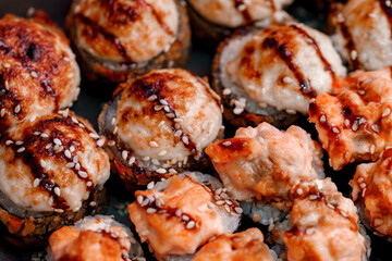 Sushi rolls baked with rice sesame seeds and with teriyaki sauce, close-up, selective focus