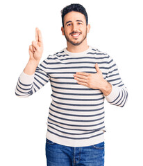 Young hispanic man wearing casual clothes smiling swearing with hand on chest and fingers up, making a loyalty promise oath
