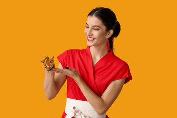 Beautiful young happy woman with golden dragon figurine on yellow background. Chinese New Year...