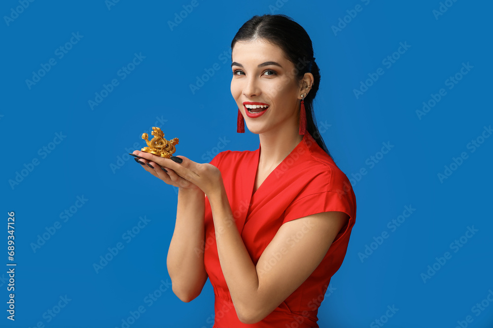 Poster Beautiful young happy woman with golden dragon figurine on blue background. Chinese New Year celebration